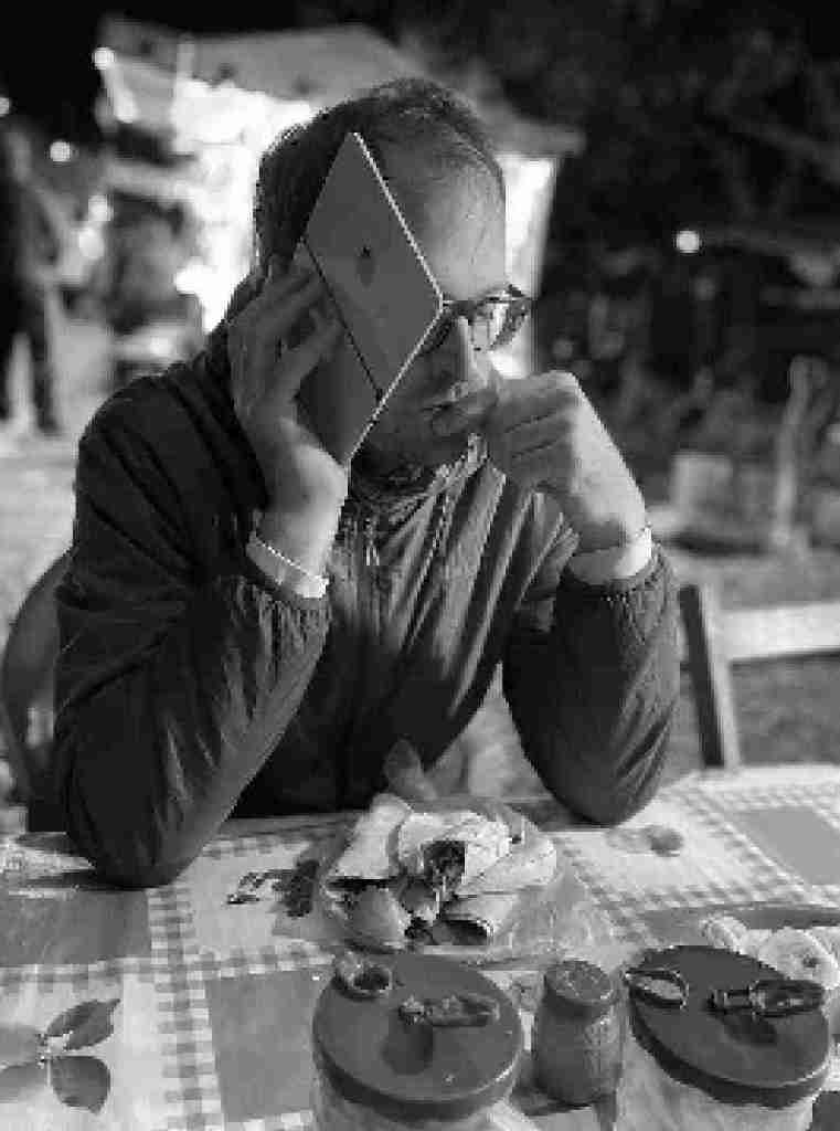 "Professional headshot" of Kert Kivaste - sitting at a table on a street taco vendor talking with Surface Duo phone